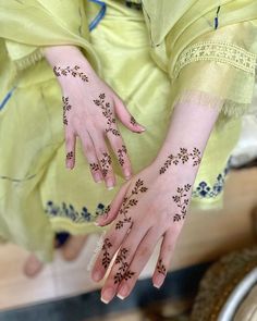 a woman's hands with hennap on her left hand and fingers, both decorated with flowers