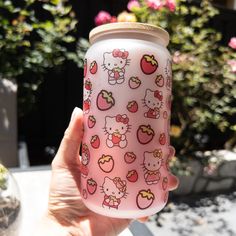 a hand holding a pink hello kitty tumbler cup