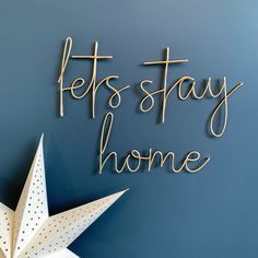 a wooden star with the words lets stay home written on it next to a blue wall