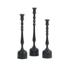 three black candlesticks sitting next to each other