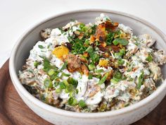 a white bowl filled with food on top of a wooden cutting board