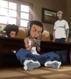 an anime character sitting on the floor looking at his cell phone while another person stands in the background