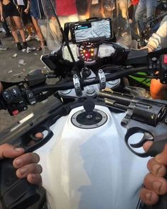 a close up of the handlebars on a motor bike with people in the background