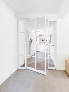 an empty room with white walls and large glass doors leading to the entrance area,