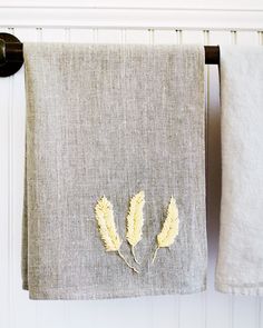 two white towels hanging on a towel rack next to a pair of black ironing pins