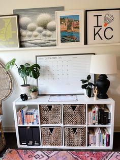 a white bookcase with wicker baskets and pictures on the wall next to it