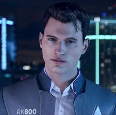 a young man wearing a suit and tie in front of a cityscape at night