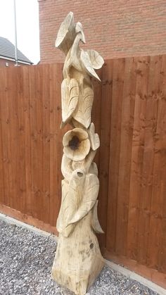 a wooden sculpture sitting next to a fence