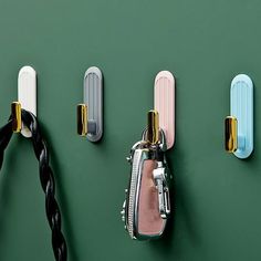 three different colored handles are attached to the green wall with black and white hair clips