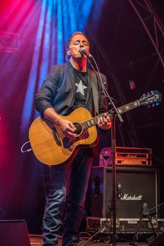 a man standing on top of a stage holding a guitar