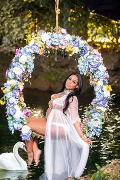 a woman is posing for a photo in front of a swan and flower circle wreath