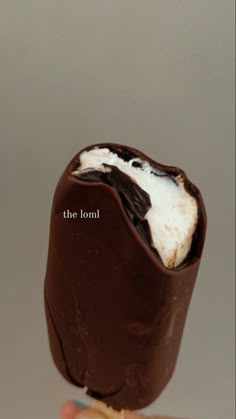 a hand holding an ice cream bar with chocolate and marshmallows in it