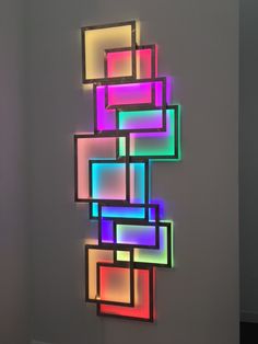 a multicolored wall hanging on the side of a white wall next to a doorway