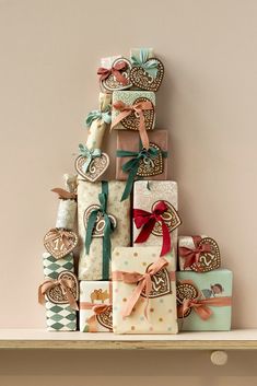 a stack of wrapped presents sitting on top of a shelf next to a christmas tree