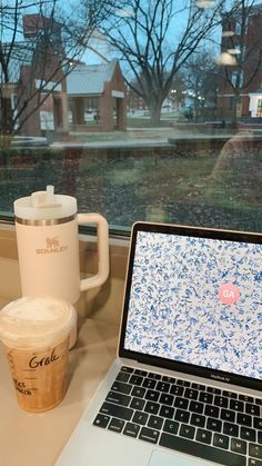 an open laptop computer sitting on top of a desk next to a cup of coffee