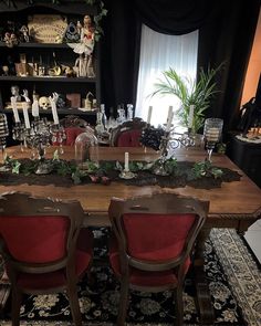 a dining room table with red chairs and christmas decorations on the top shelf above it