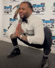 a man with dreadlocks sitting on the floor in front of a wall and clapping