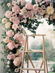 a wooden step ladder with flowers on it and greenery around the top is an arch