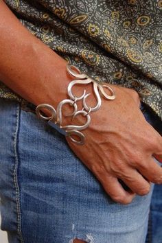 a person wearing a silver bracelet with flowers on it's wrist and holding their hands in the other hand