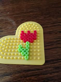 a heart shaped object made out of legos on top of a wooden table with beads