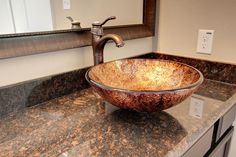 a bowl shaped sink sitting on top of a bathroom counter next to a faucet