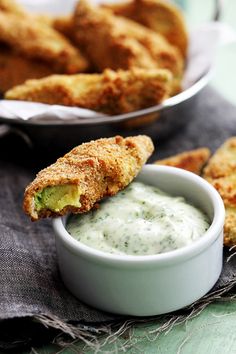 some fried food is in a bowl and on a napkin next to another plate with dipping sauce