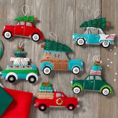 christmas ornaments with cars and trees hanging from them on a wooden table next to a santa hat