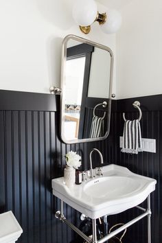 a white sink sitting under a bathroom mirror next to a wall mounted faucet