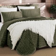 a bed with green and white comforters on top of it