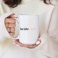 a woman holding a white coffee mug with the word bride written in pink on it