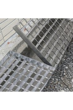 a metal grate sitting on the side of a building next to a cement wall