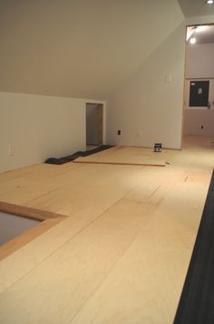 an unfinished room with wood flooring in the foreground and white walls on the other side