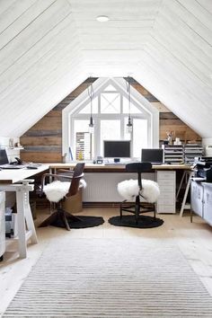 an attic office with two desks and chairs in the corner, along with a rug on the floor