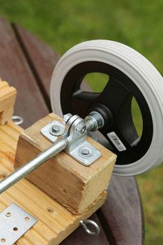 a close up of a piece of wood and metal on a table with wheels in the background