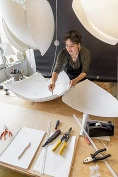 a woman sitting at a table working on an object with scissors and pliers next to it