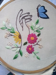 a close up of a embroidery on a piece of cloth with flowers and a butterfly