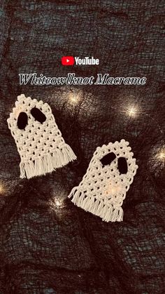 two white crocheted earrings with fringes on top of a black cloth background