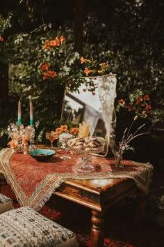 a table with flowers and candles on it in front of a mirror that is hanging from the ceiling