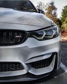 the front end of a silver car parked in a parking lot