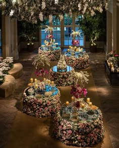 a room filled with lots of tables covered in flowers and lit up candles next to windows