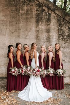 a group of women standing next to each other in front of a wall with flowers