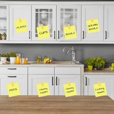 post - it notes are stuck to the cabinets in a kitchen with white cupboards