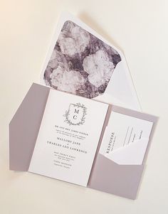 the wedding stationery is laid out on top of the card and envelope, which has been folded to reveal an elegant monogrammed design