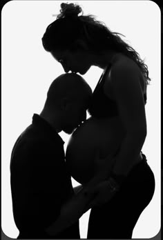 black and white photograph of a pregnant woman with her husband looking down at her belly