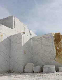 white marble blocks are stacked up against each other in front of a large rock formation