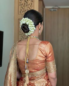 a woman in an orange and gold sari with flowers in her hair