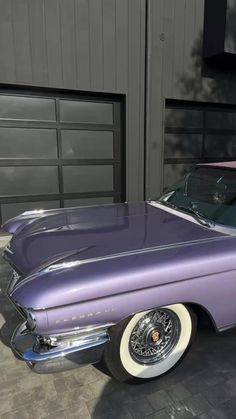 an old purple car parked in front of a garage