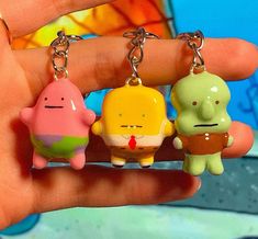 three little cartoon characters are hanging from tiny key chains