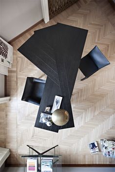 an overhead view of a living room with black furniture and wood flooring on the walls