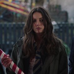 a woman with blood on her face holding a candy cane